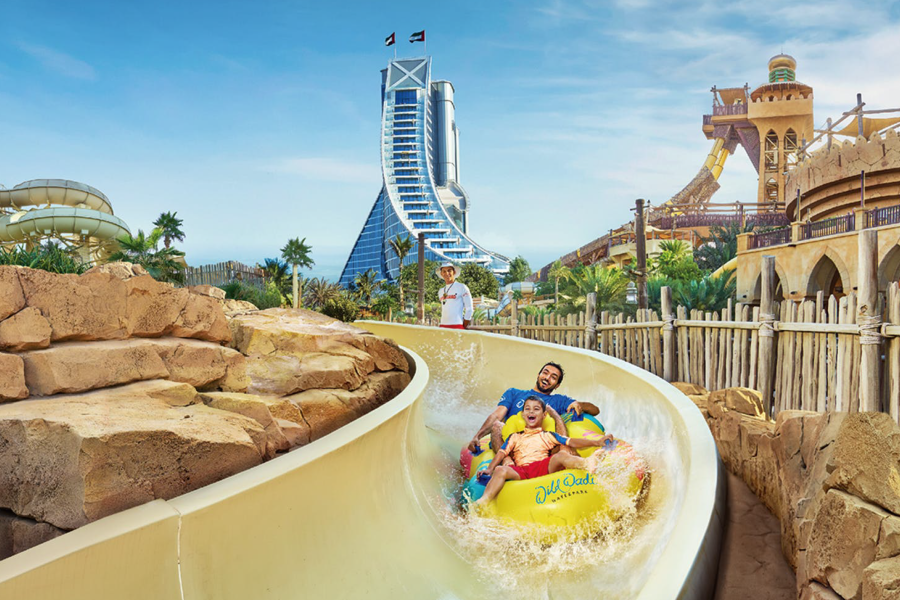 family enjoying wild wadi waterpark dubai ith jumeirah beach hotel in the background